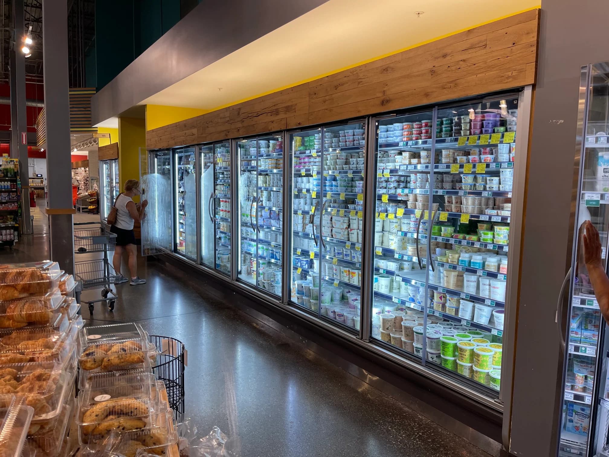 Glass-door refrigerated dairy cases in a grocery store aisle
