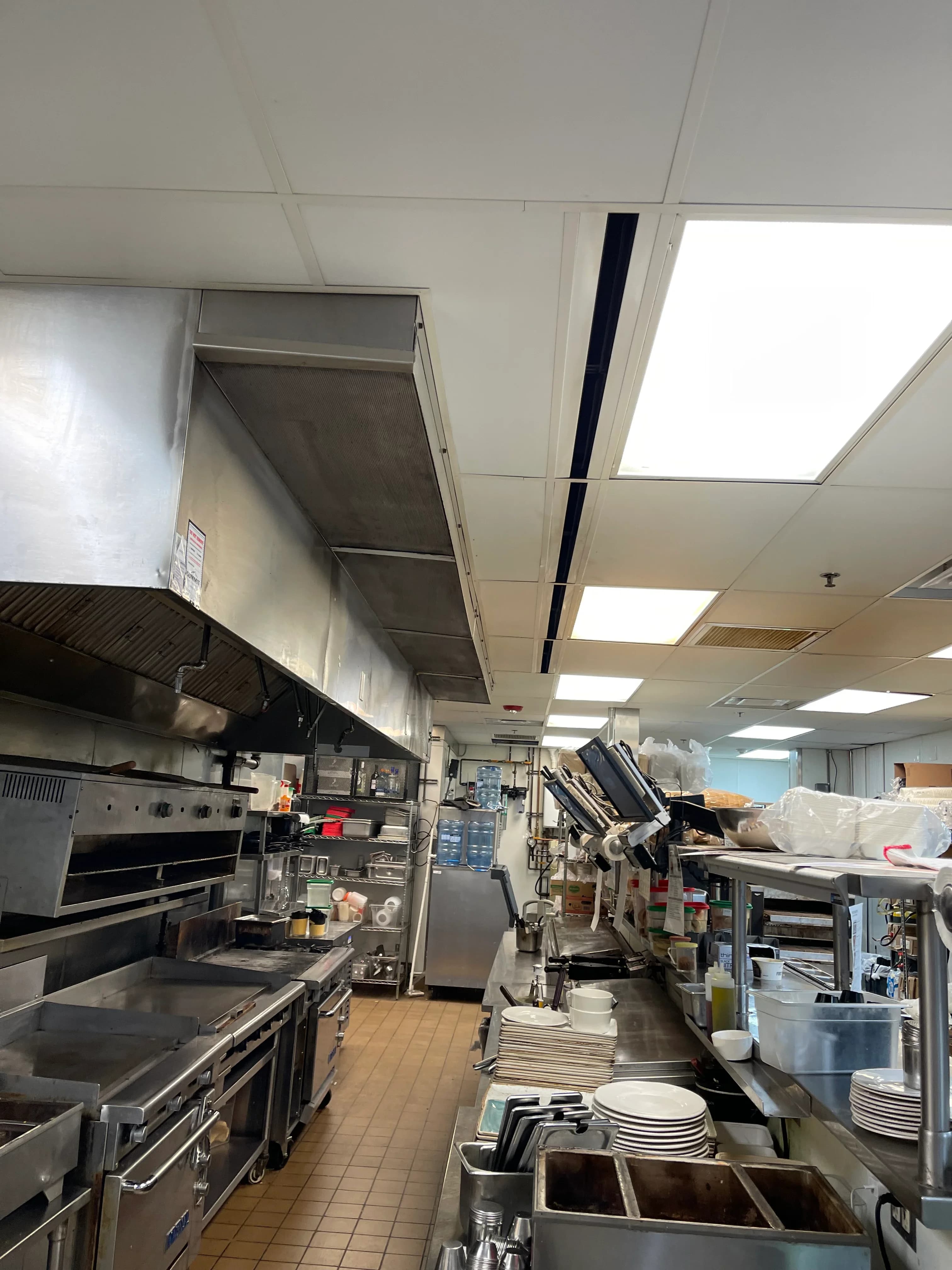 A busy restaurant cook line with griddles, ranges and an exhaust hood